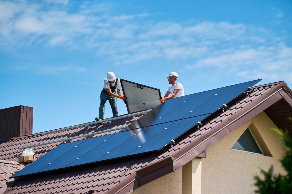 Installateurs posant des panneaux photovoltaïques sur le toit d’une maison